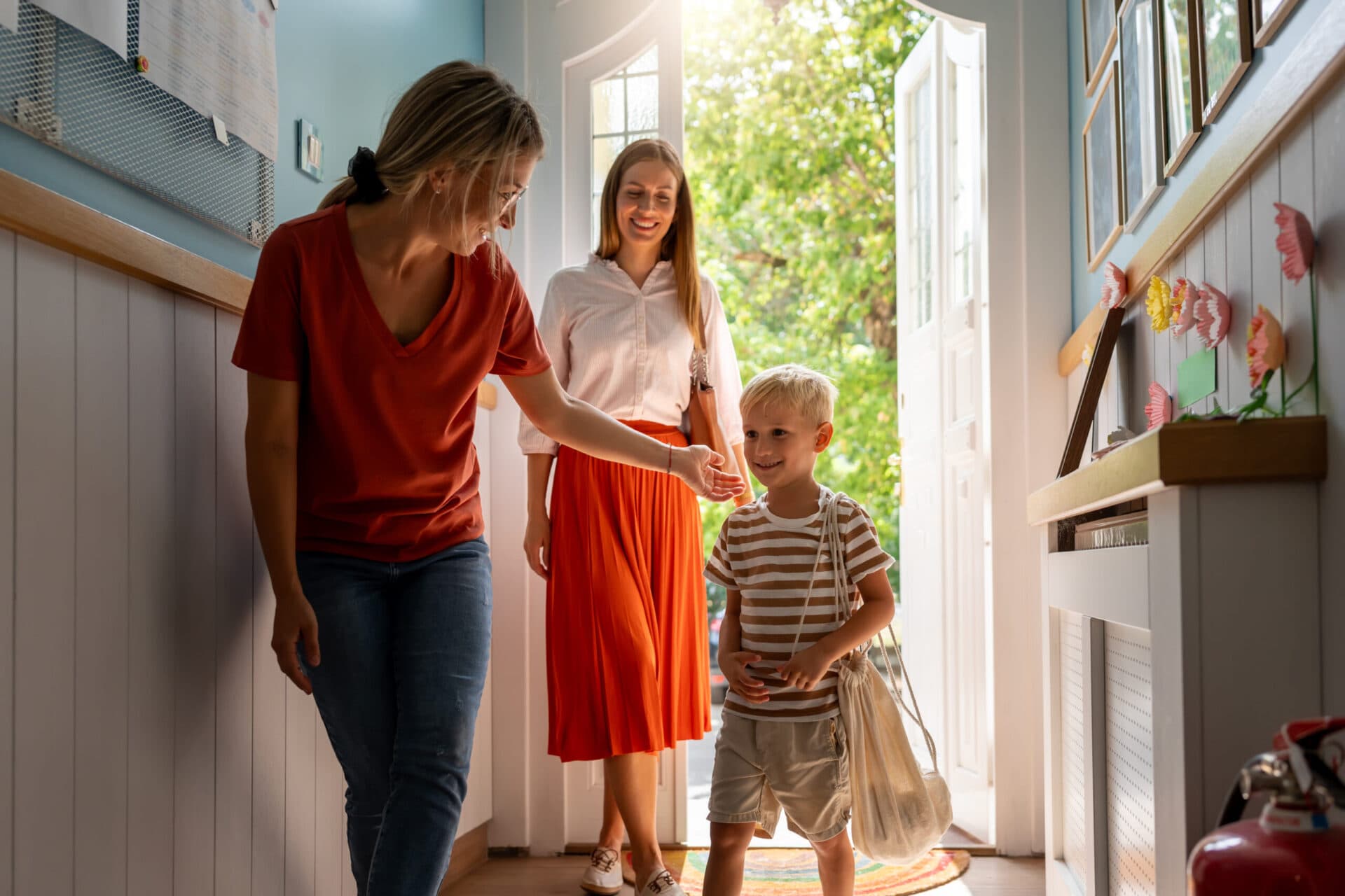 A parent collecting her son at the classroom door while a teacher sees them out