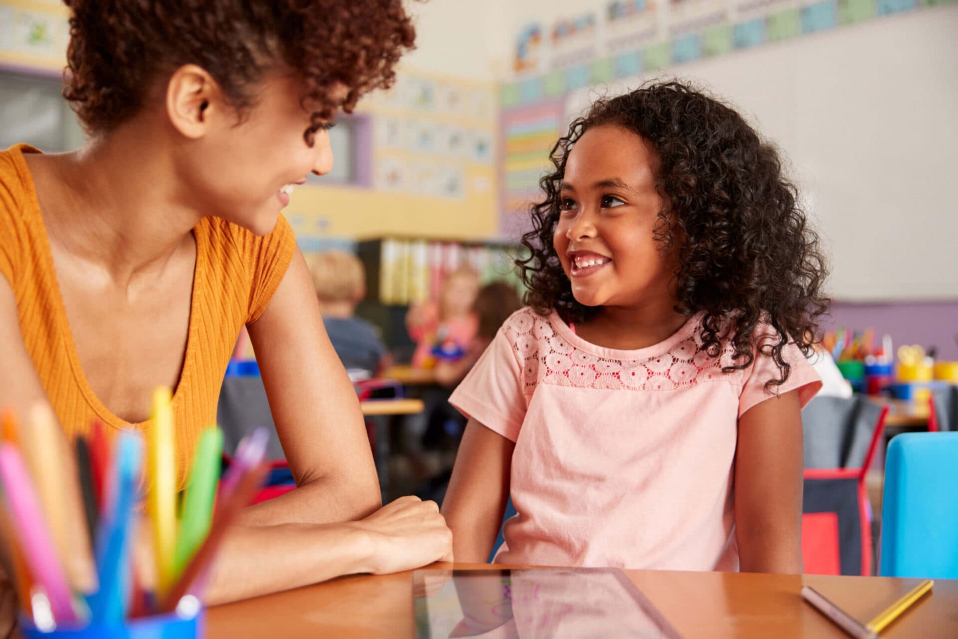 A teacher and a child smiling at each other in a Kids Cove classroom