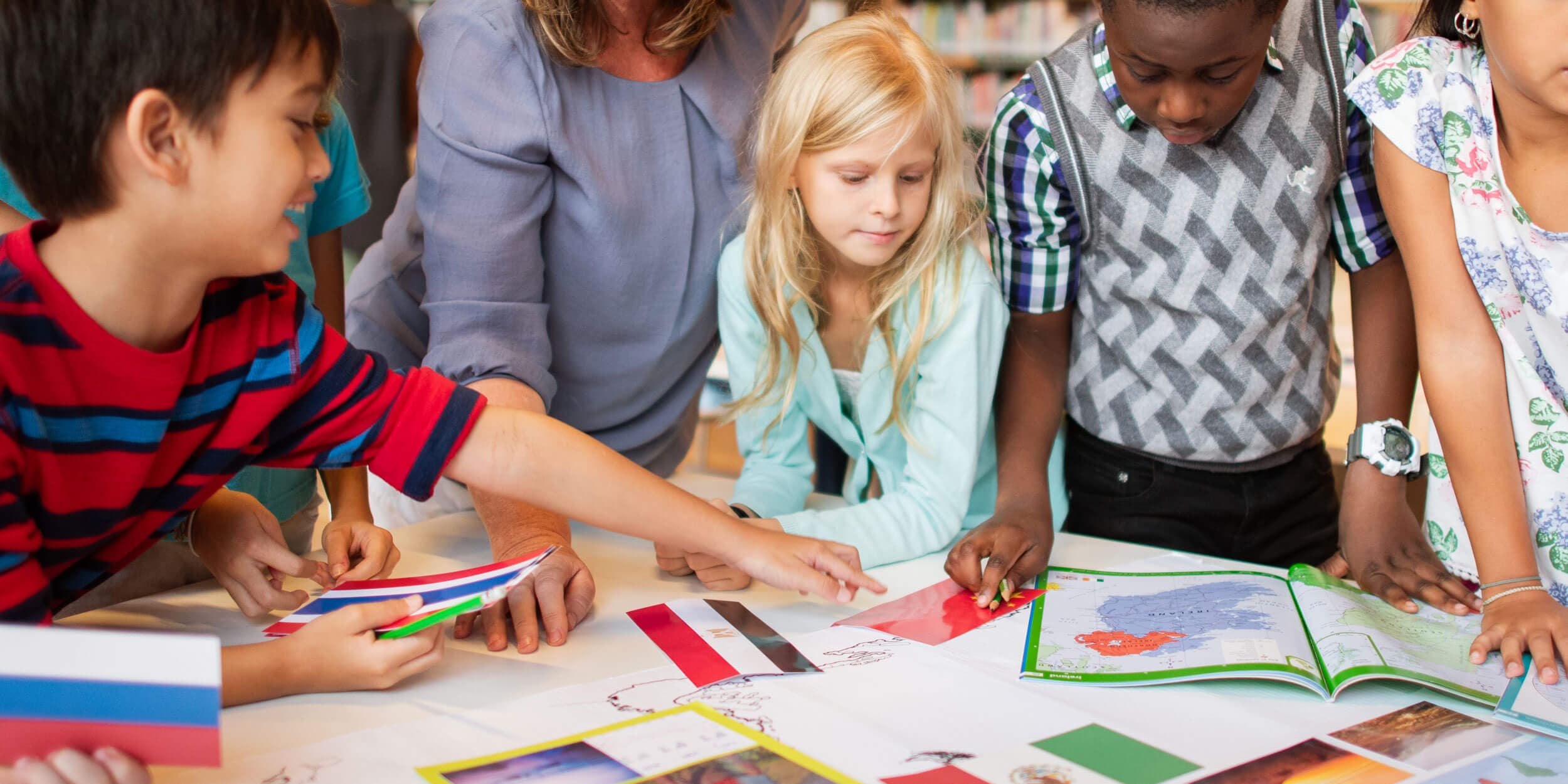 A teacher and group of children working together on a colourful craft project