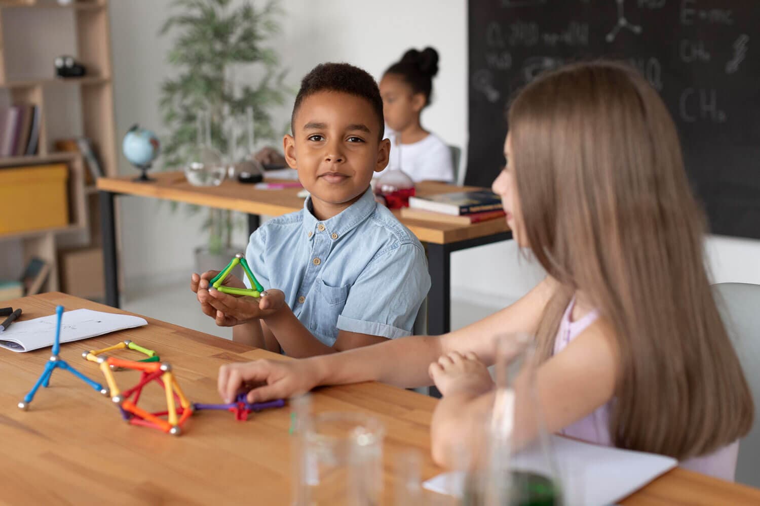 A boy holding up a geometric construction toy he has built at a workbench