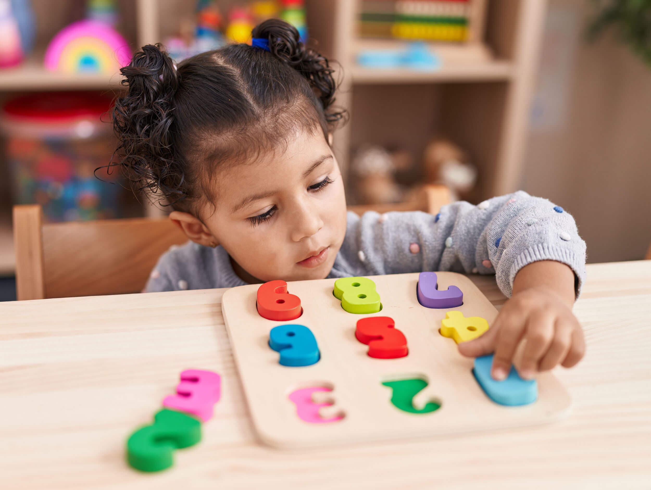 A girl fitting colourful wooden letters into a puzzle board