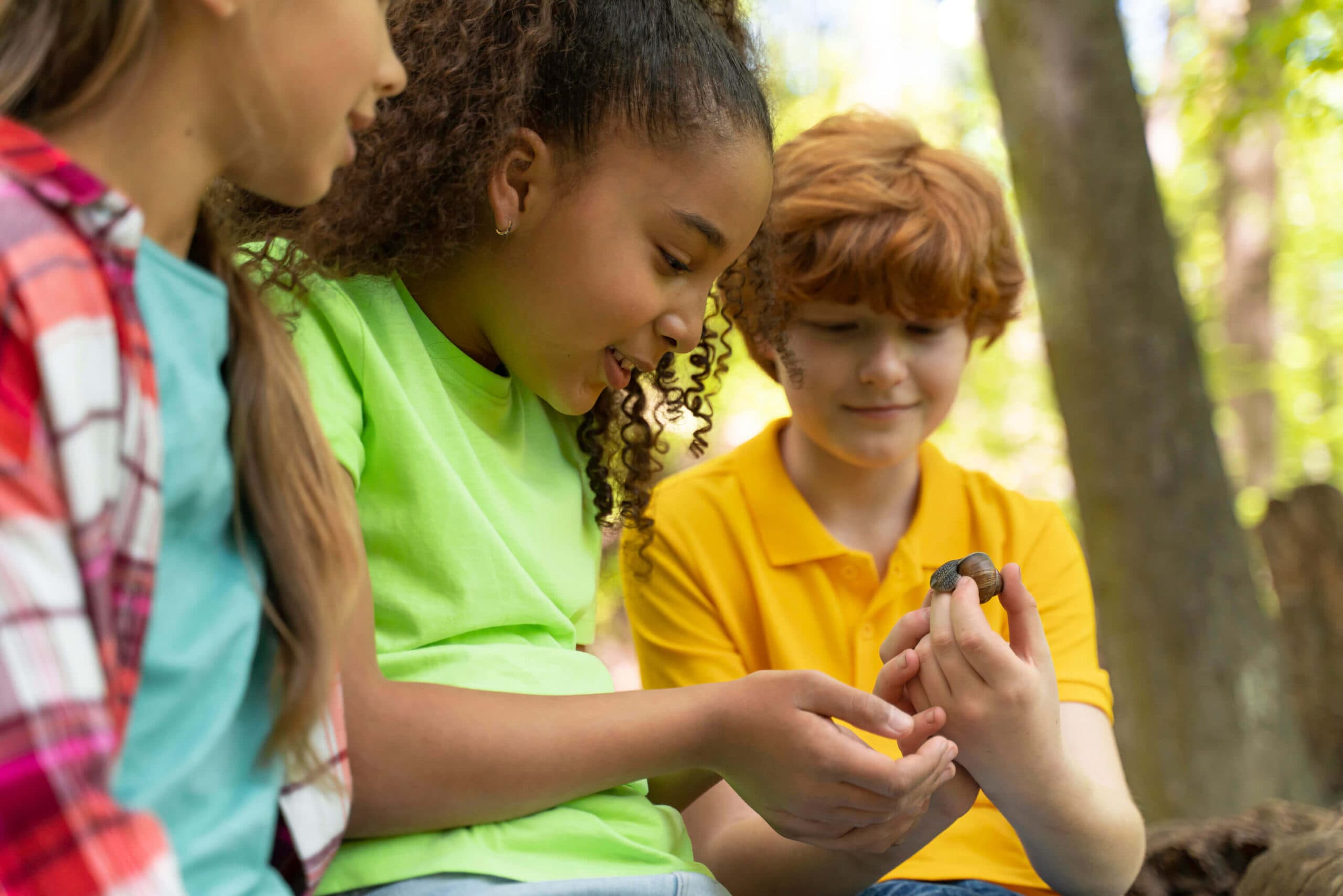 Two children outdoors examining something small cupped in their hands