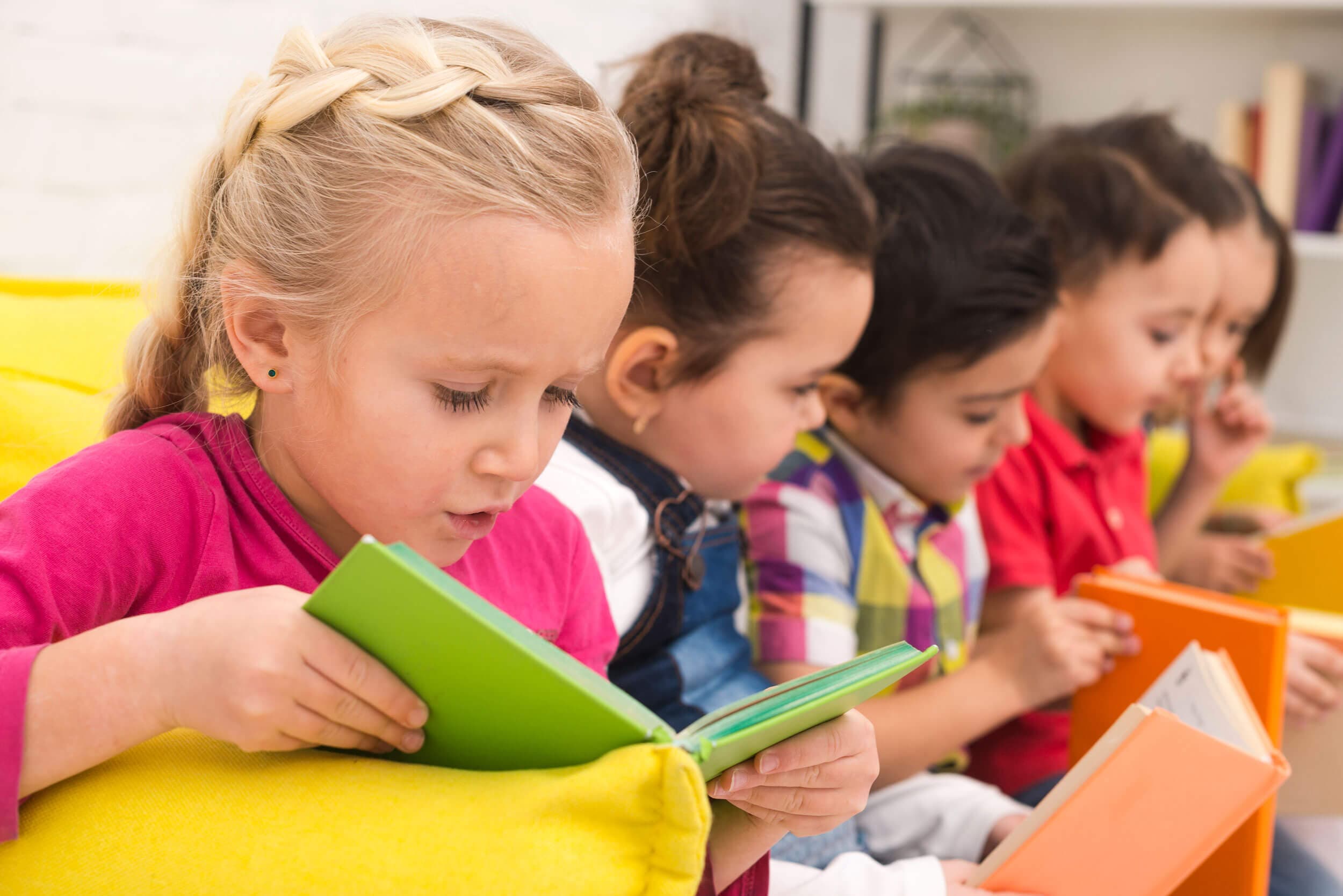 A row of children holding up coloured books while reading together